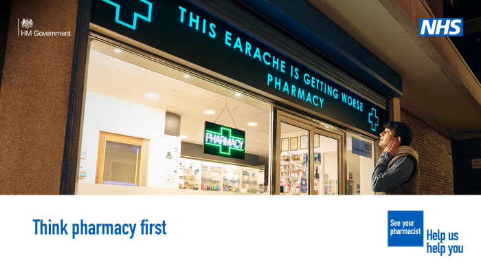 A person is standing outside a pharmacy . The sign above the pharmacy reads 